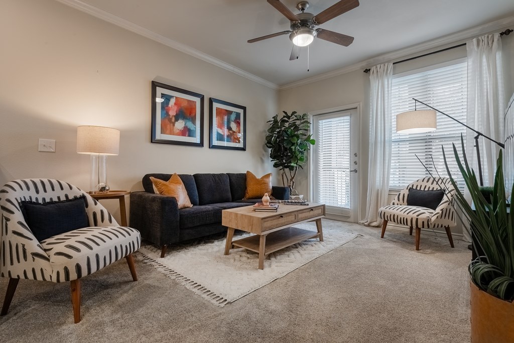 a living room with a couch and chairs and a ceiling fan