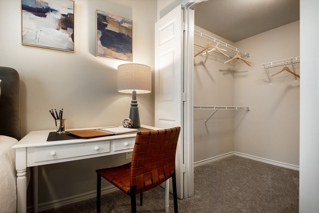a bedroom with a desk with a chair and a closet