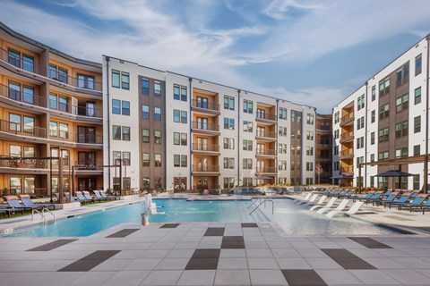A large swimming pool in front of apartment buildings.