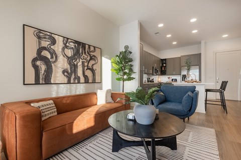 A living room with a brown couch and a large abstract painting on the wall.