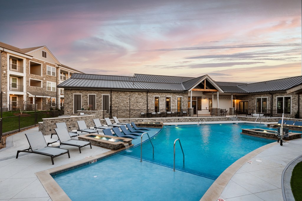 a swimming pool with lounge chairs next to an apartment building
