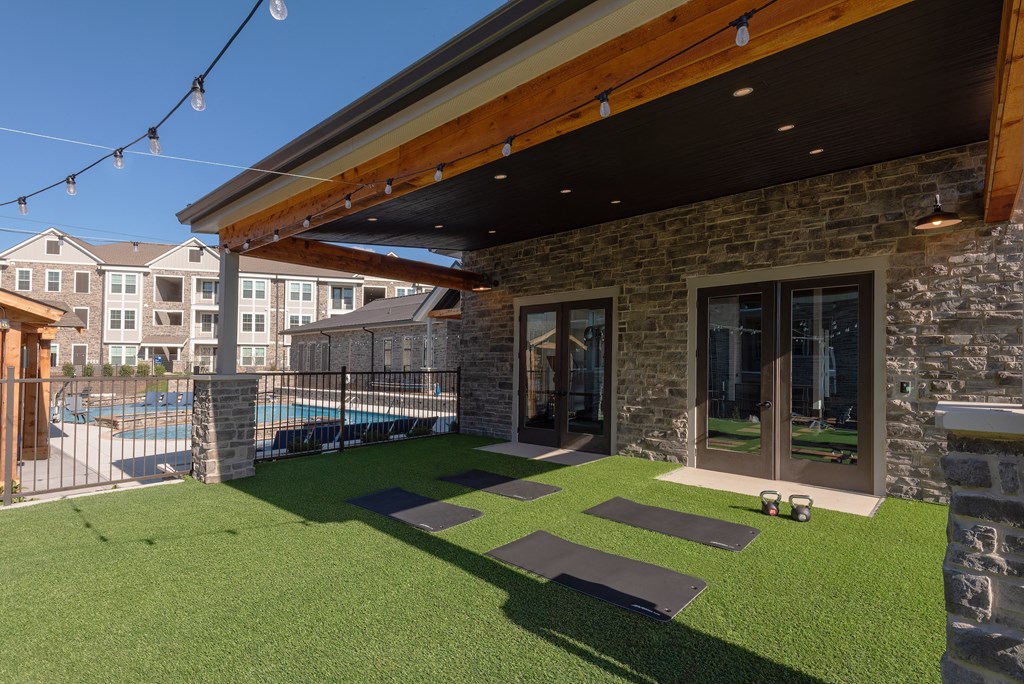 a backyard with grass and yoga mats and a pool