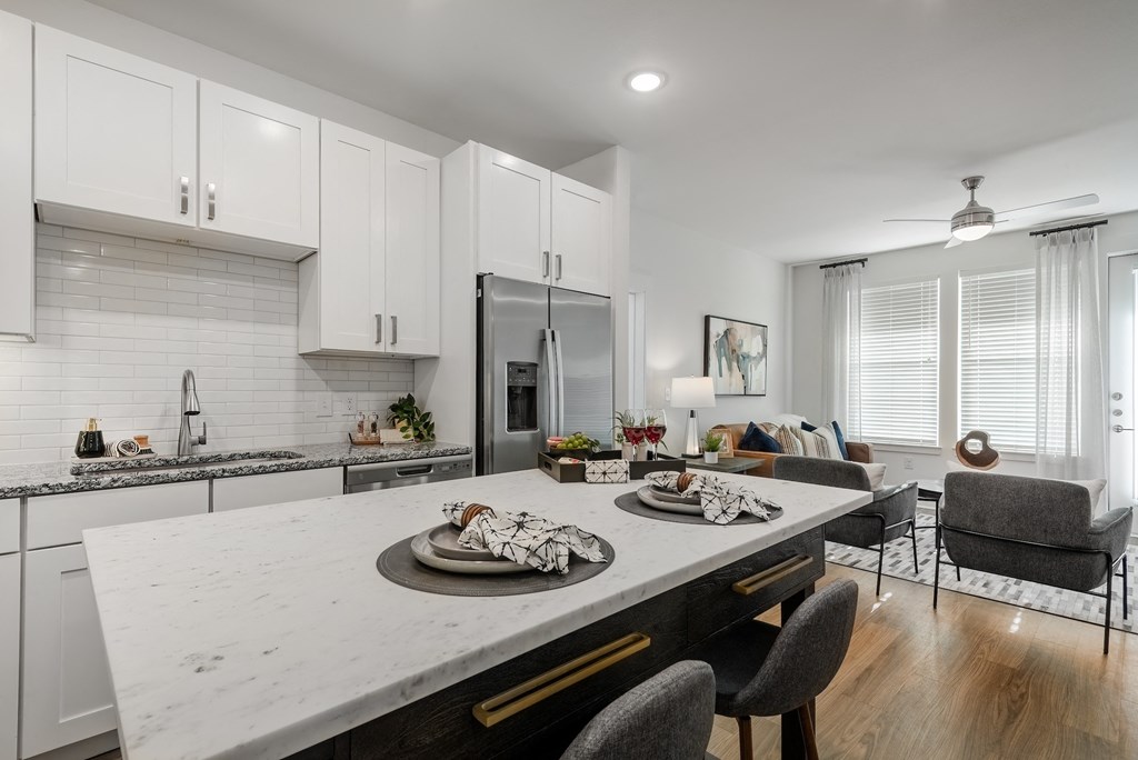 an open kitchen and living room with a marble counter top