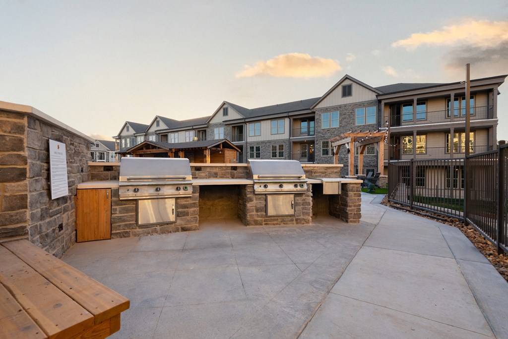 an outdoor kitchen with a grill and a building in the background