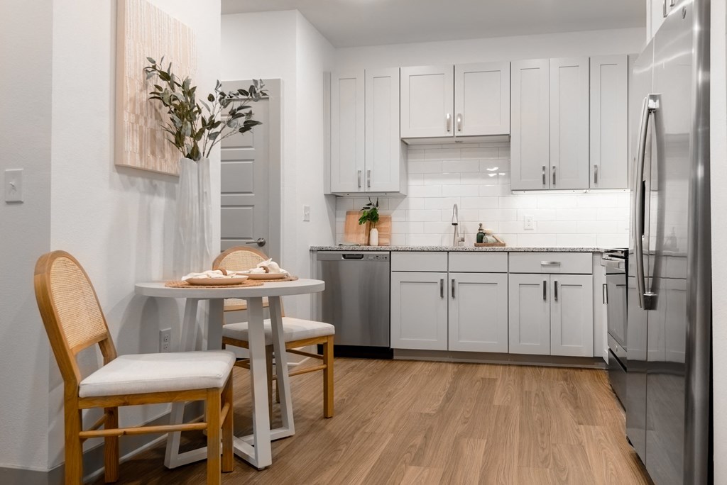 a small kitchen with white cabinets and a table and chairs