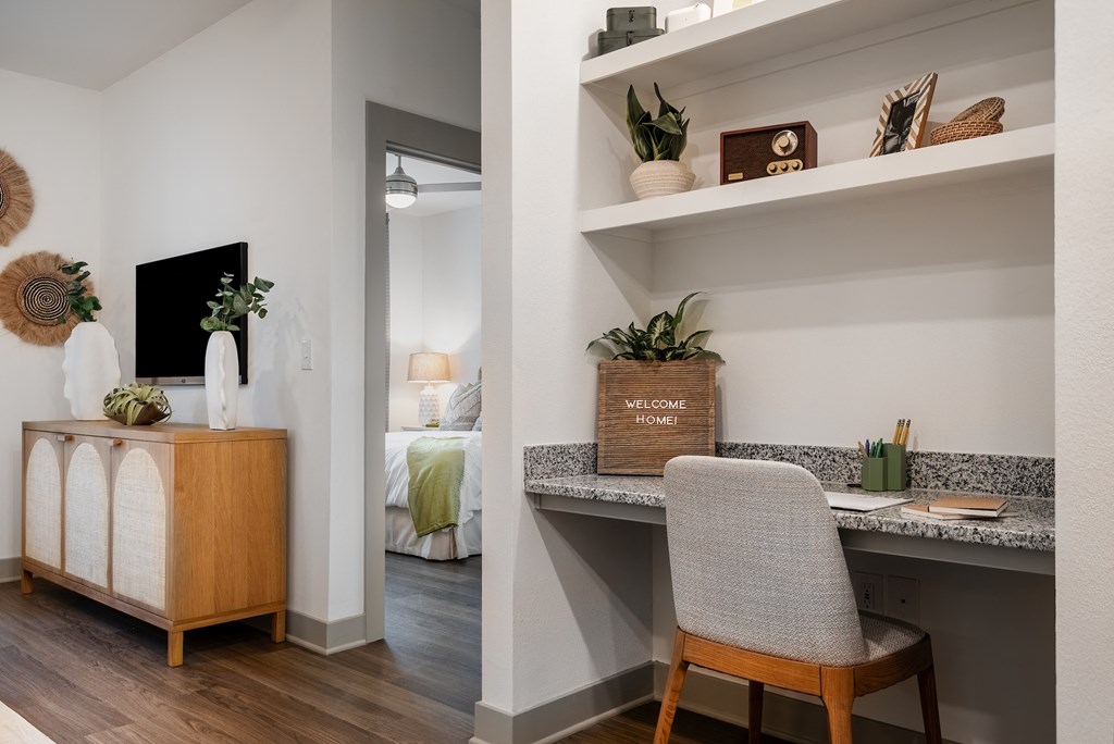 an office with a desk and a chair in a room with a bedroom