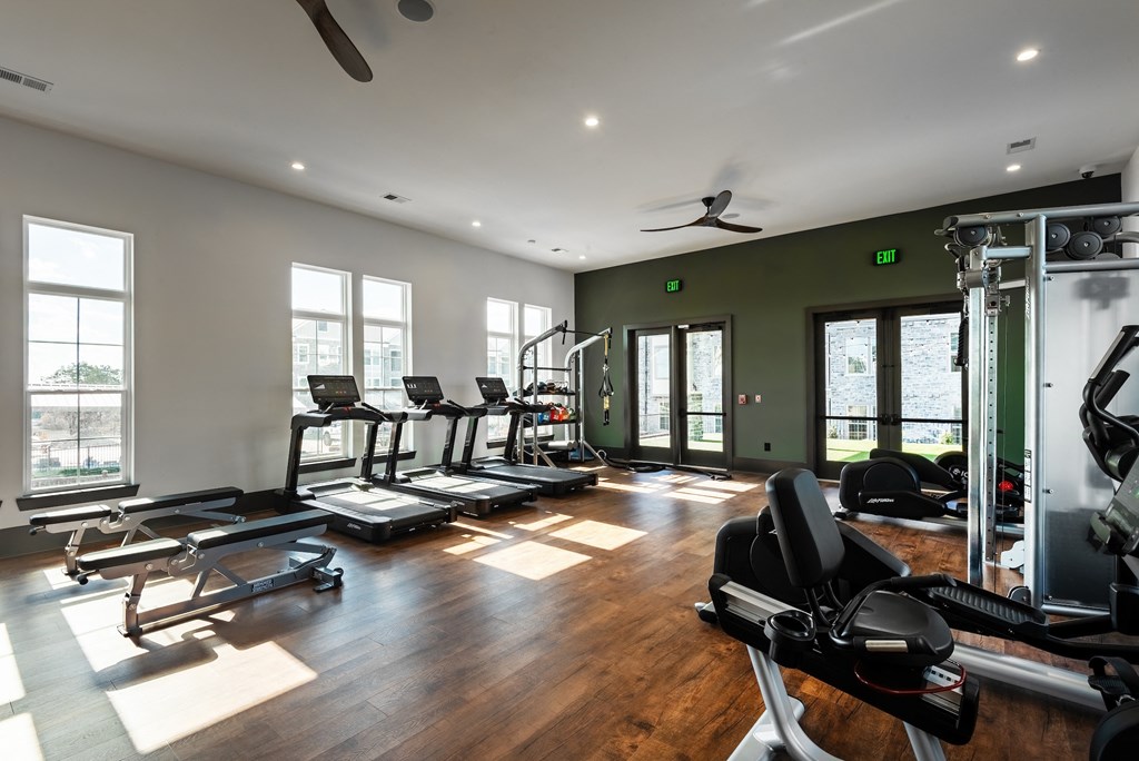 the gym has plenty of exercise equipment and windows