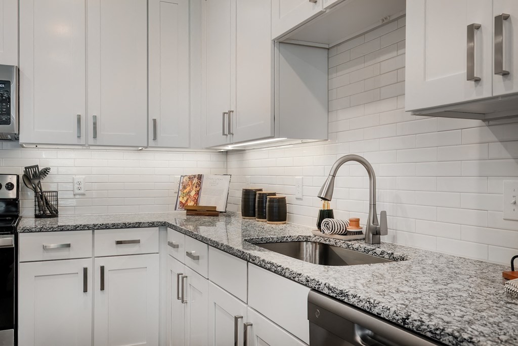 a kitchen with white cabinets and granite counter tops and a sink
