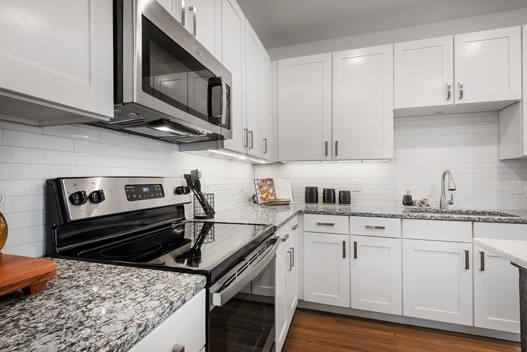 an updated kitchen with white cabinets and granite counter tops
