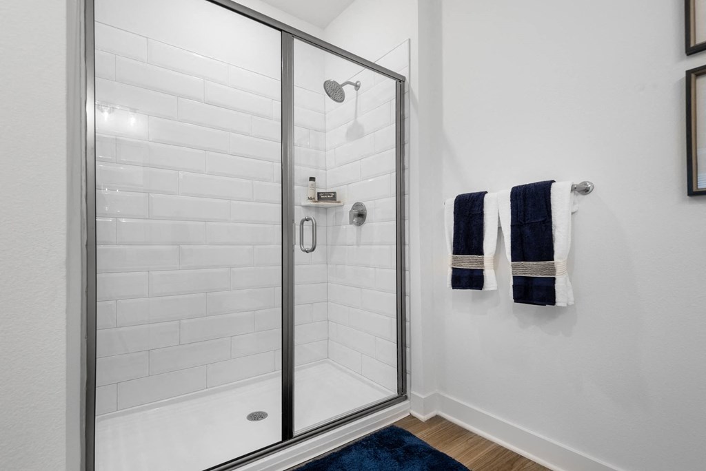 a shower with a glass door in a white bathroom
