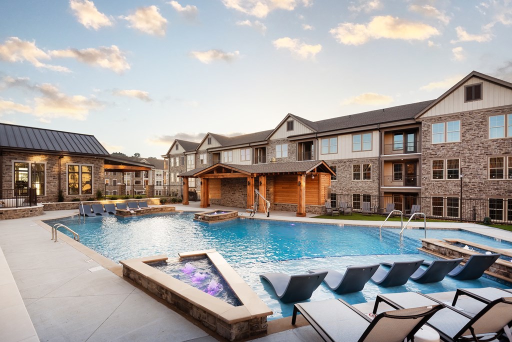 a large swimming pool with chairs in front of an apartment building