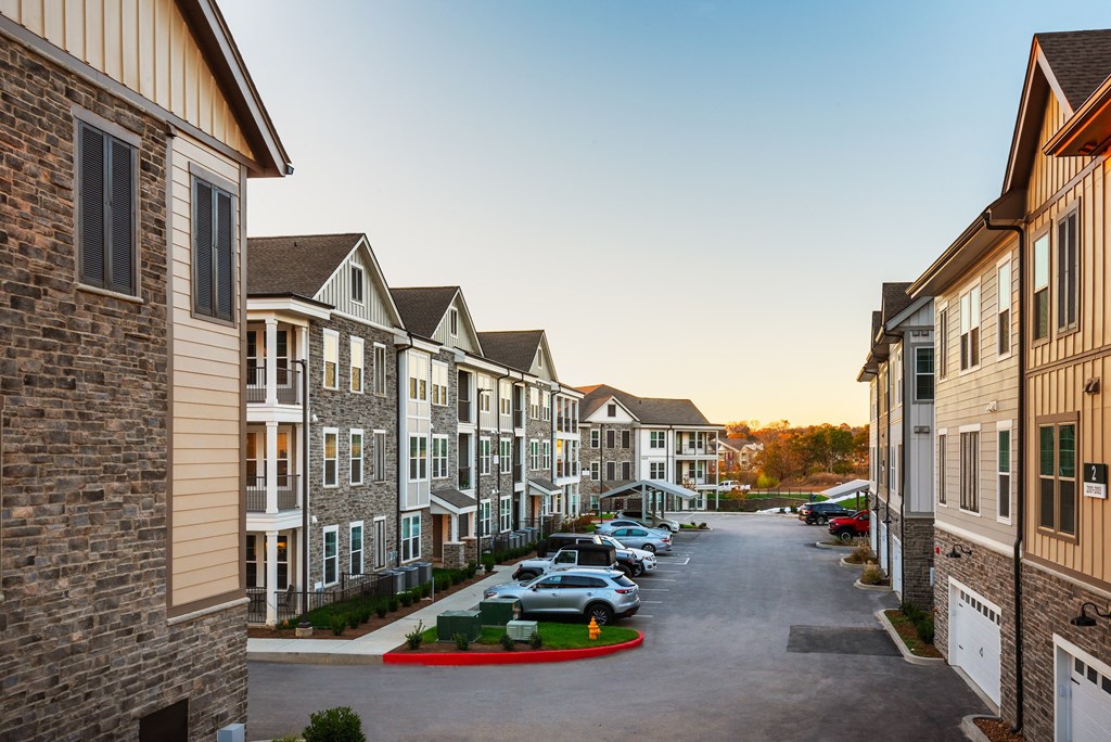 a row of town houses with cars parked in a street