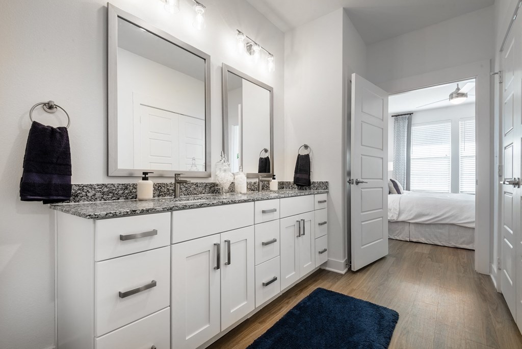 a bathroom with two sinks and mirrors and a door to a bedroom