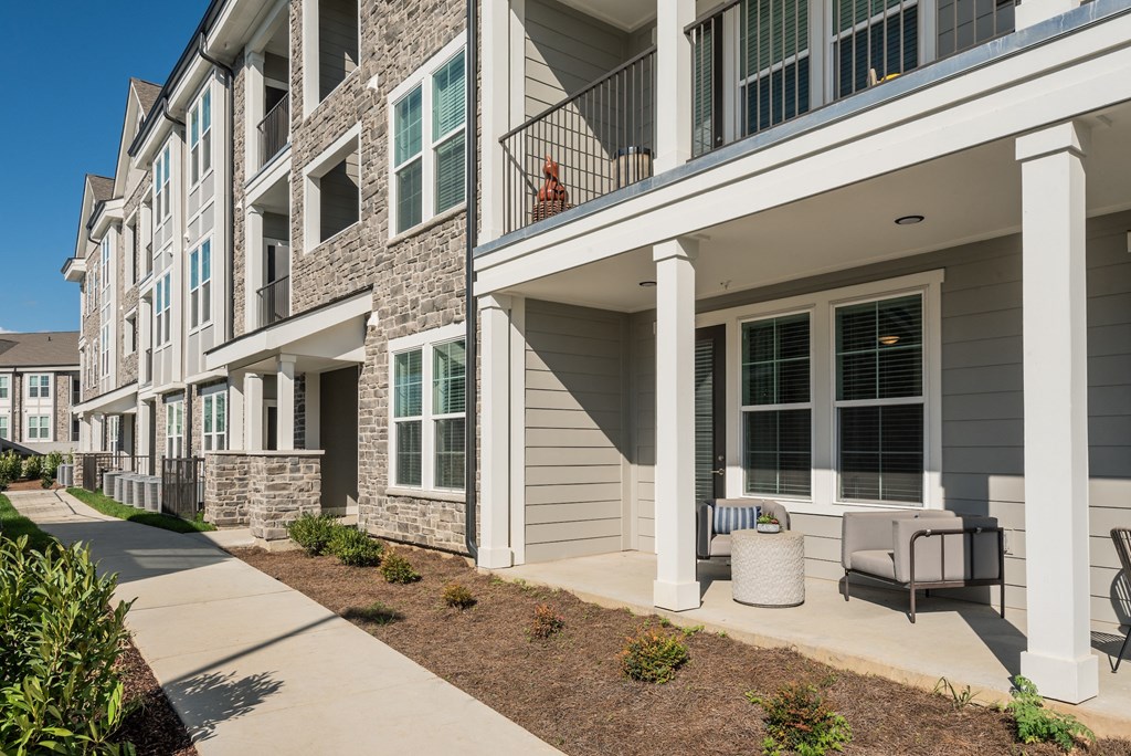 an exterior view of an apartment building with a sidewalk and chairs