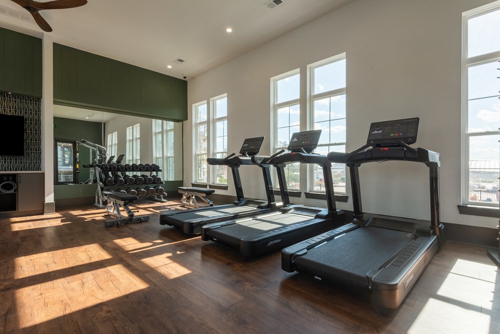 a gym with treadmills and other exercise equipment in a building with large windows