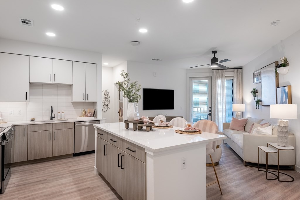 A modern kitchen with a white island and wooden floors.