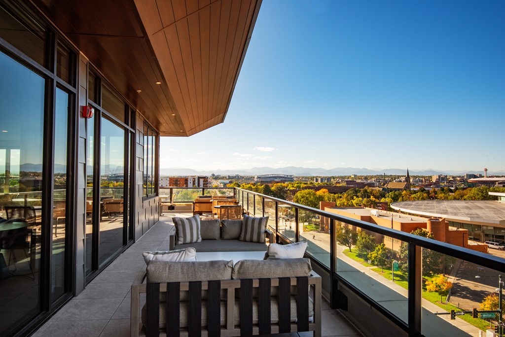 A balcony with a couch and pillows overlooks a cityscape.
