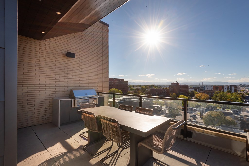 A table and chairs are set up on a patio with a view of the city.