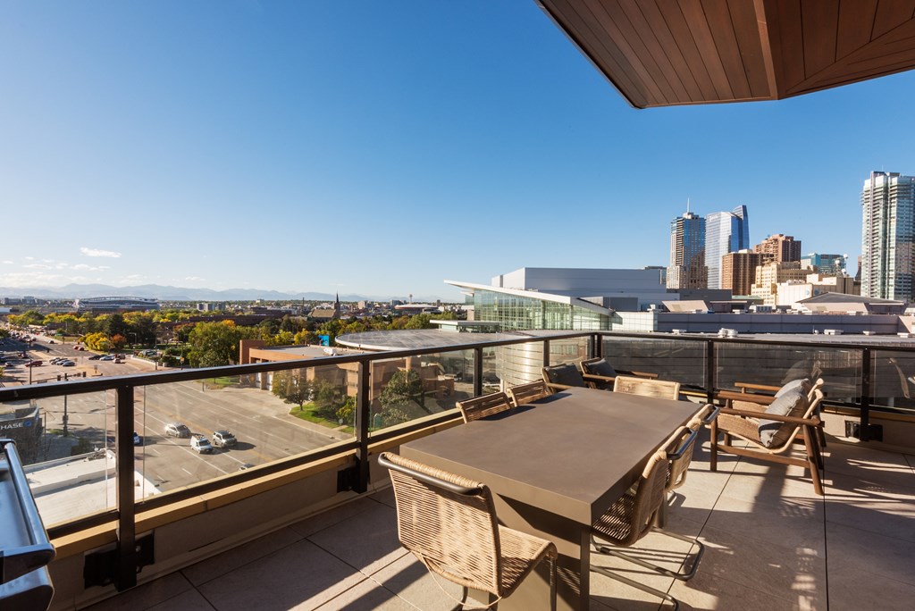 A balcony with a table and chairs overlooking a cityscape.