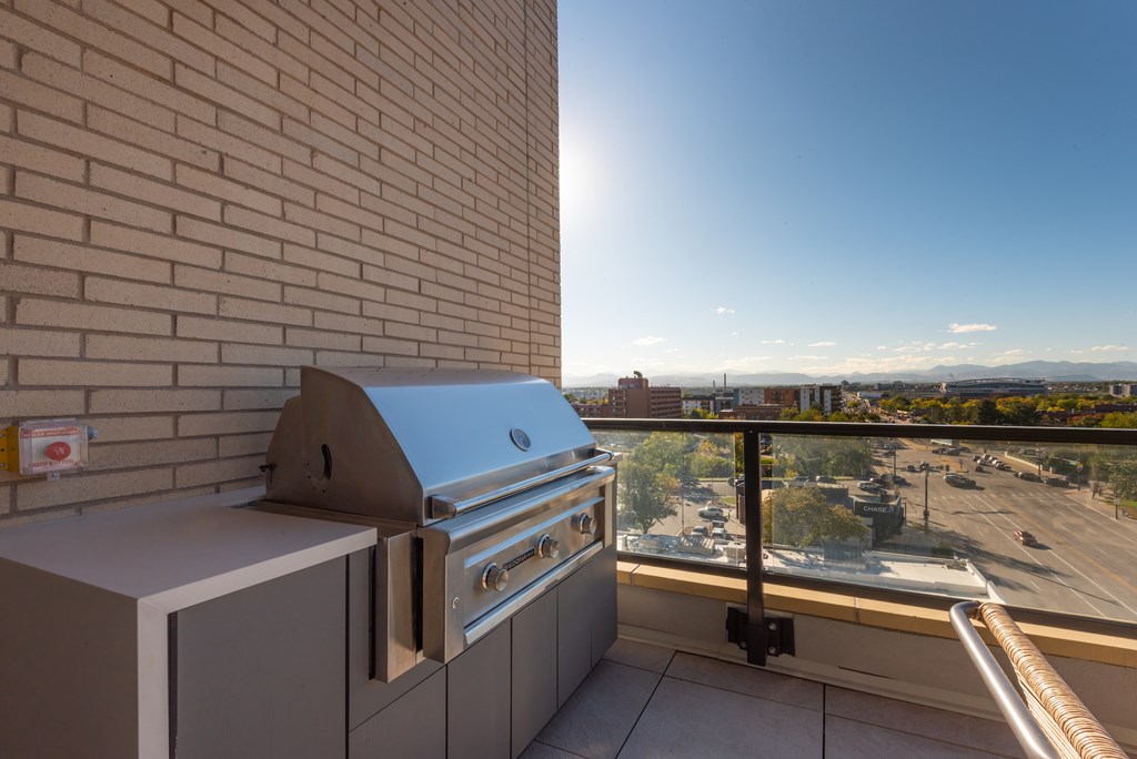 A stainless steel grill is on a patio with a view of the street and mountains.