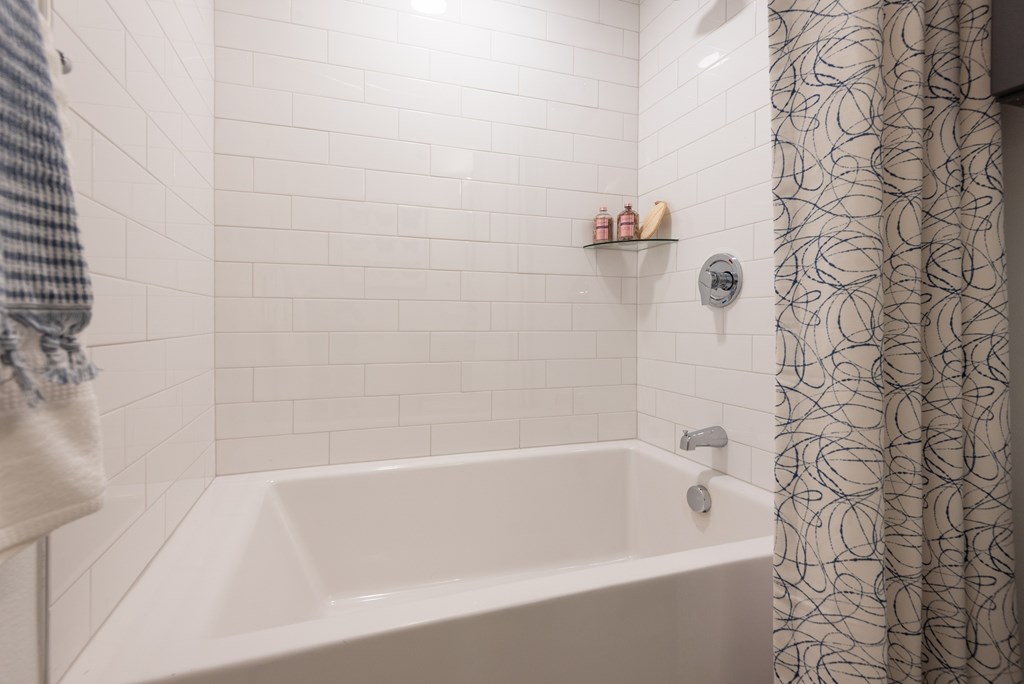 A white bathtub in a bathroom with a shower curtain on the right.