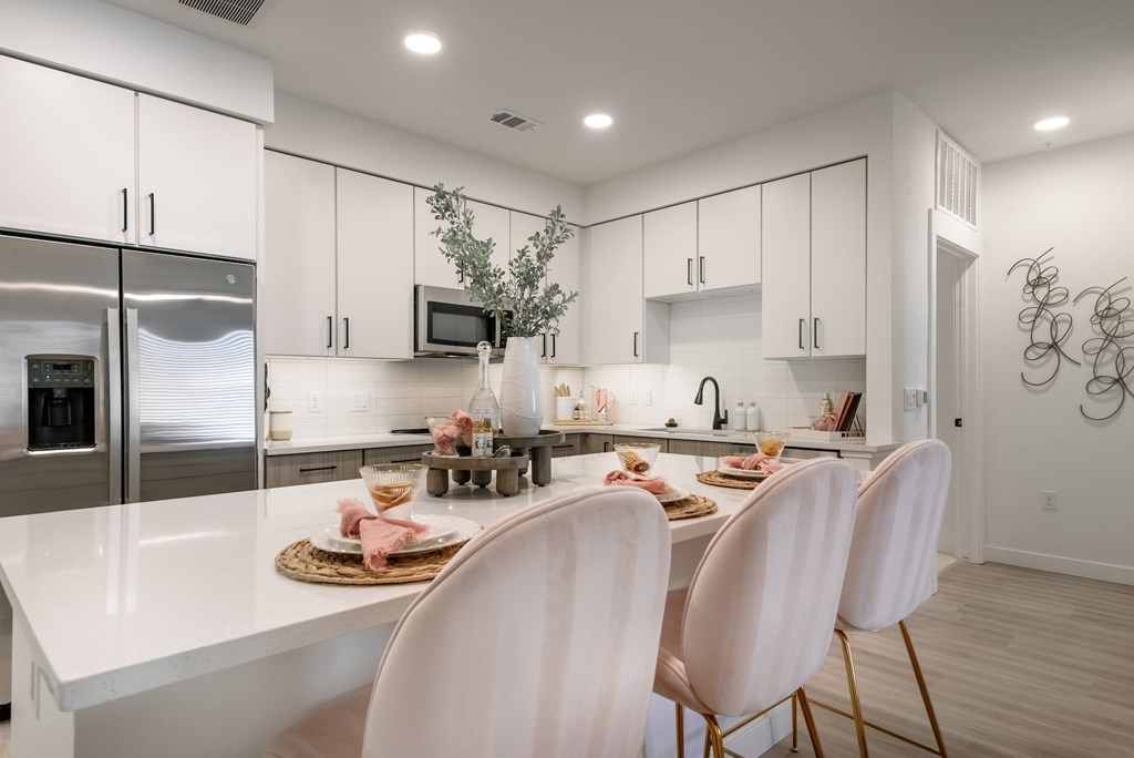 A modern kitchen with white cabinets and a dining table set for two.