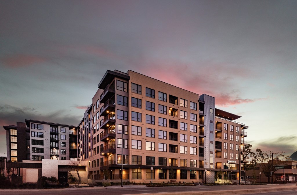 A modern multi-story building with a mix of beige and black balconies.