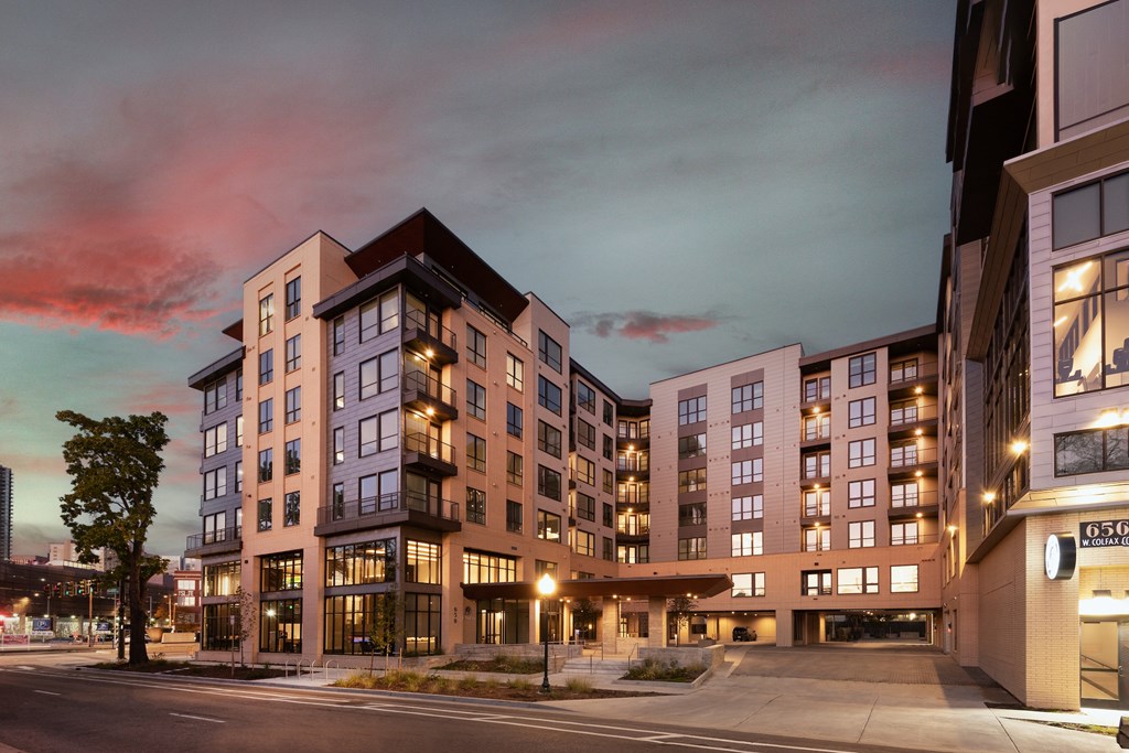 A modern apartment building with a parking lot in front.