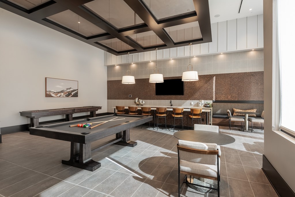 A billiard table is in the middle of a room with a bench and chairs.