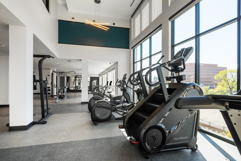 A gym with a treadmill, elliptical machines and other exercise equipment.