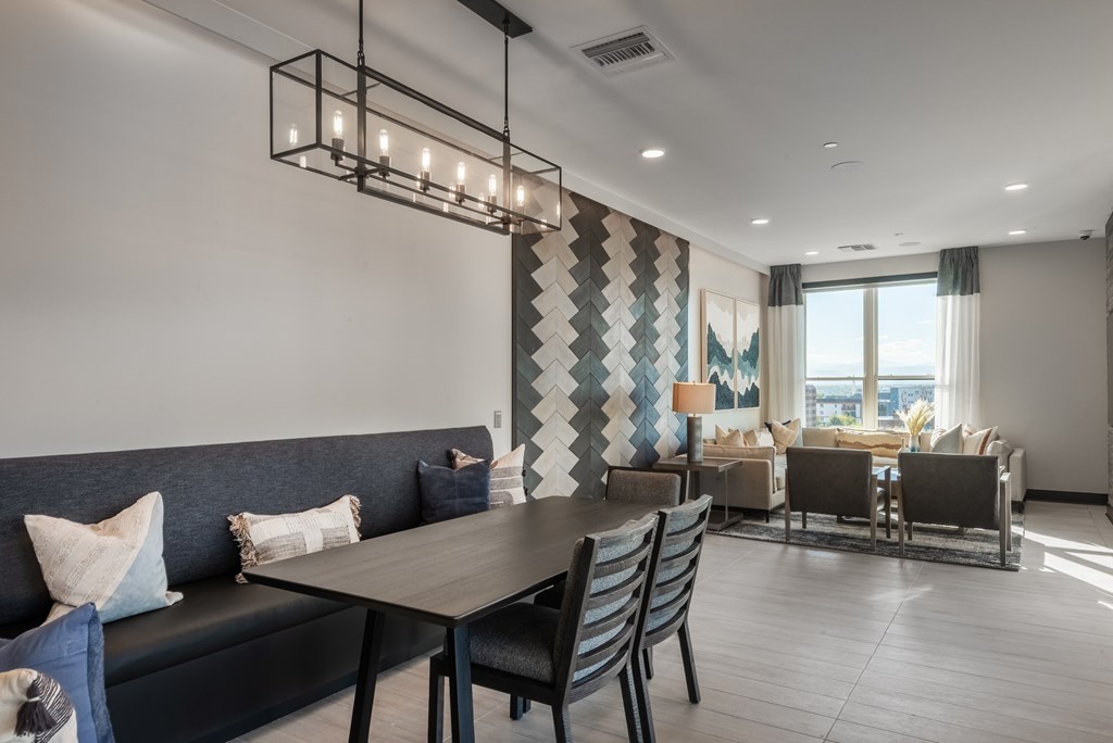 A modern dining room with a dark grey sofa and a wooden table.