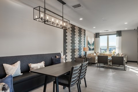 A modern dining room with a dark grey sofa and a wooden table.