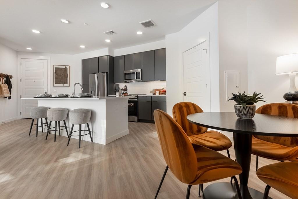 A modern kitchen with a bar area and a dining table set with chairs.
