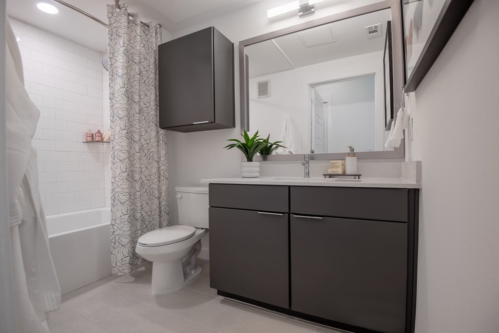 A bathroom with a toilet, sink, and mirror.