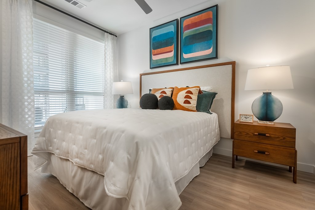 A bedroom with a white bed and a wooden nightstand.