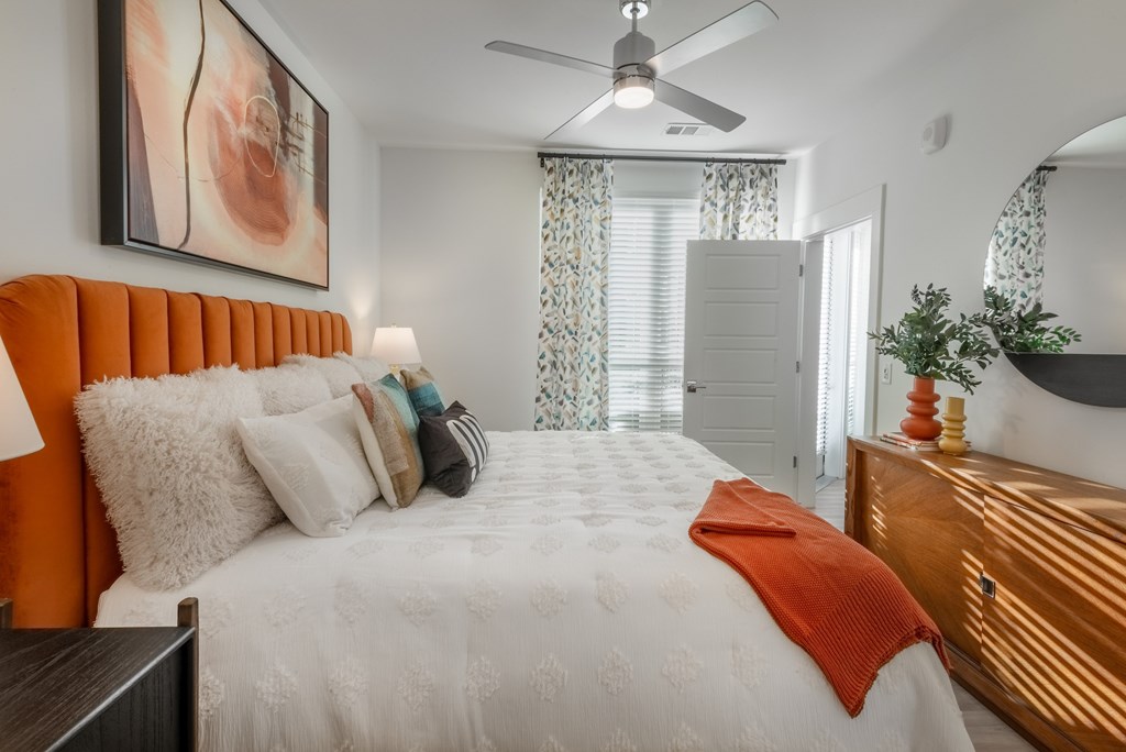 A bedroom with a white bed and orange headboard.