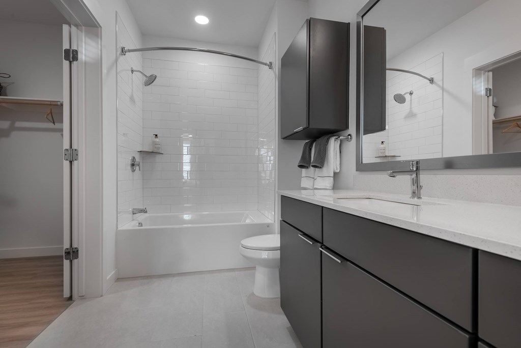 A modern bathroom with a white tub and dark grey cabinets.