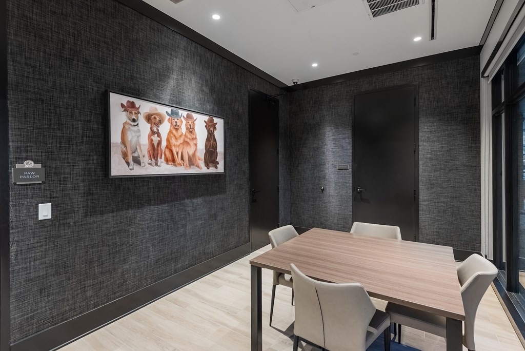 A conference room with a large table and chairs and a painting of dogs on the wall.