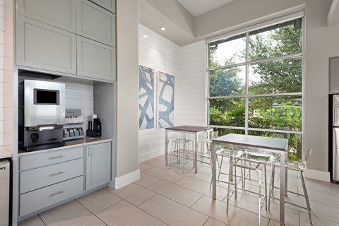 a kitchen with a bar and a table with chairs and a microwave