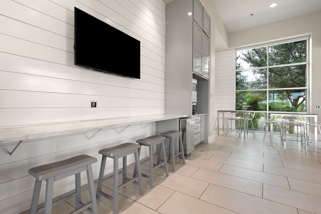 a bar with stools and a television on the wall