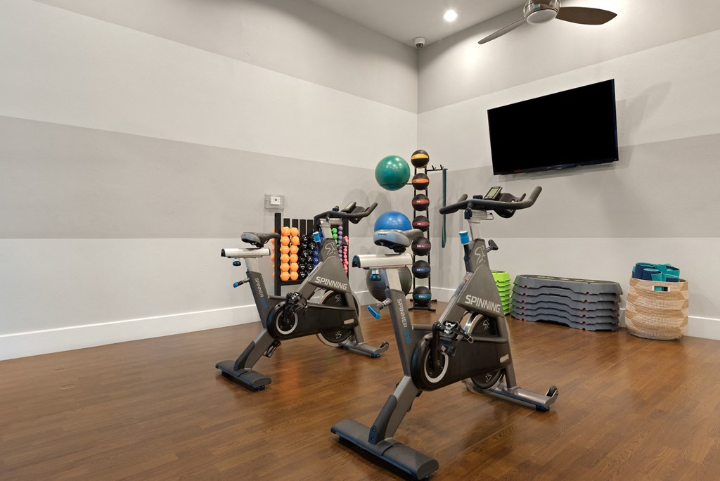 a room with two exercise bikes and a tv on the wall