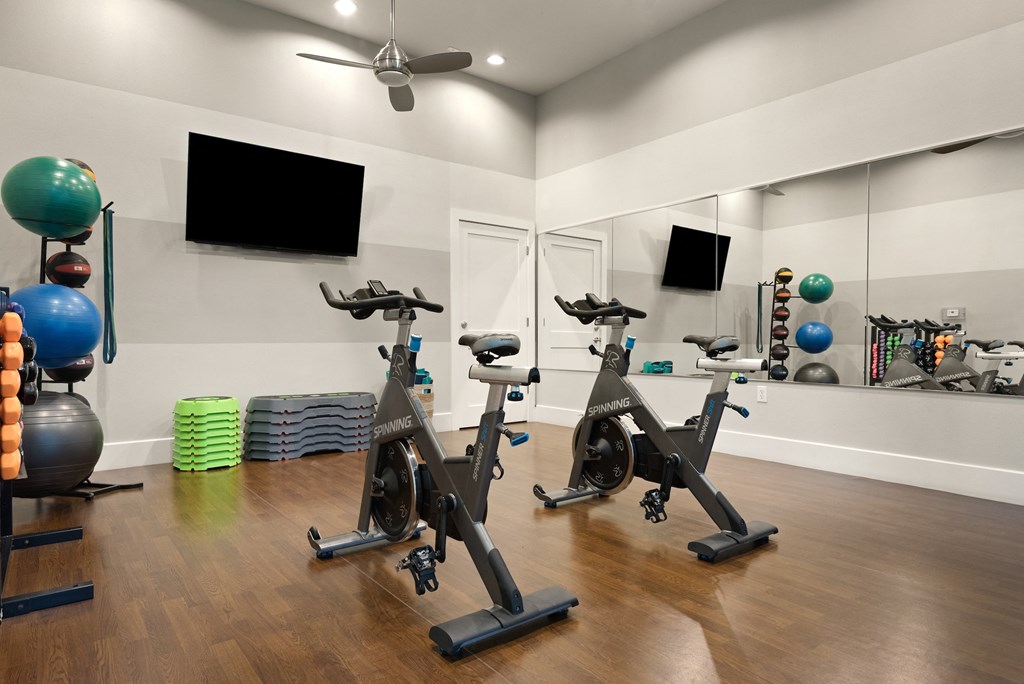 a spacious fitness room with cardio equipment and a flat screen tv