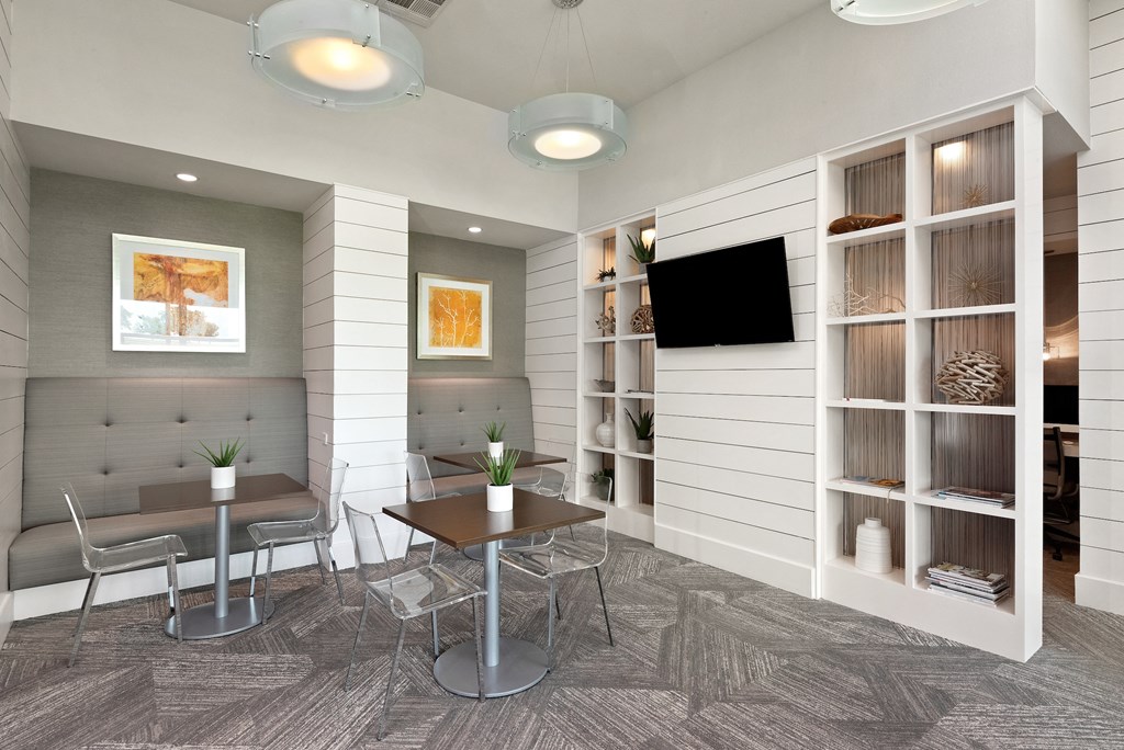 a room with a table and chairs and a television on the wall