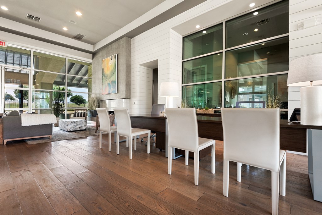 a dining area with a long wooden table and white chairs