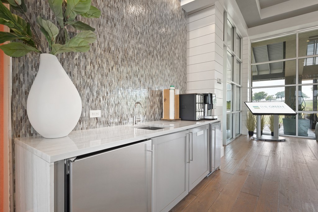 a kitchen with white cabinets and a white vase with a plant in it