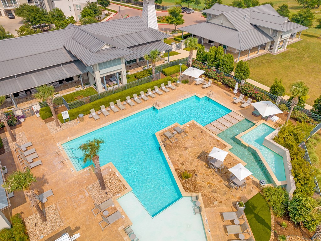 an aerial view of a resort style pool with lounge chairs and umbrellas