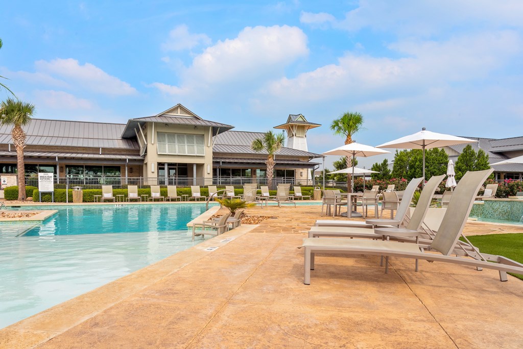 a resort style pool with lounge chairs and umbrellas
