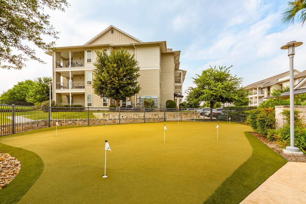 a putting green with a building in the background