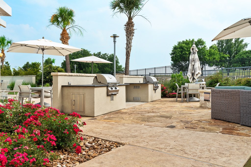 a patio with bbq grills and umbrellas at the enclave at woodbridge