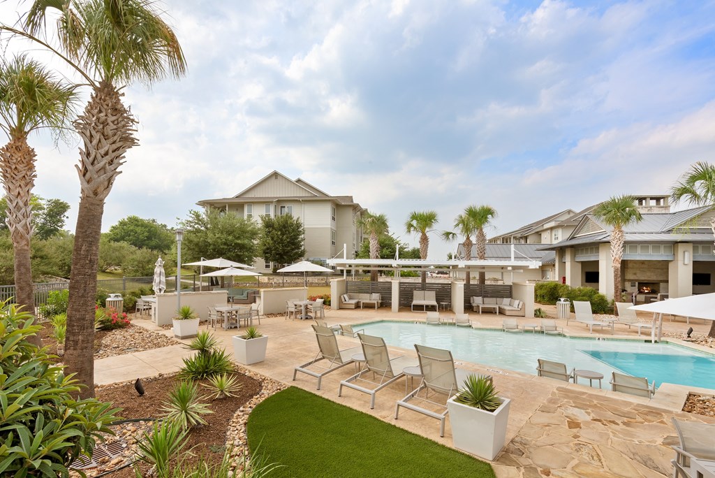 a resort style pool with lounge chairs and umbrellas